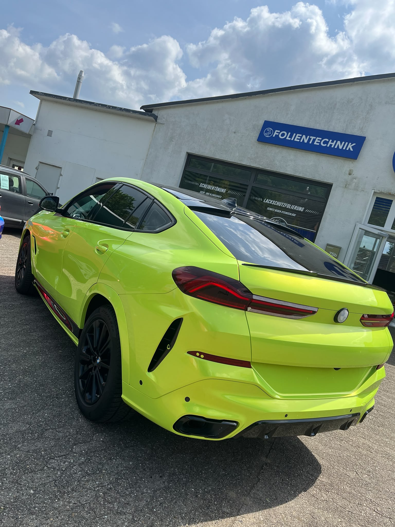 BMW mit hochwertiger Neon-Vollfolierung vor der Tipp Topp Autoglas & Folientechnik Werkstatt in Stade